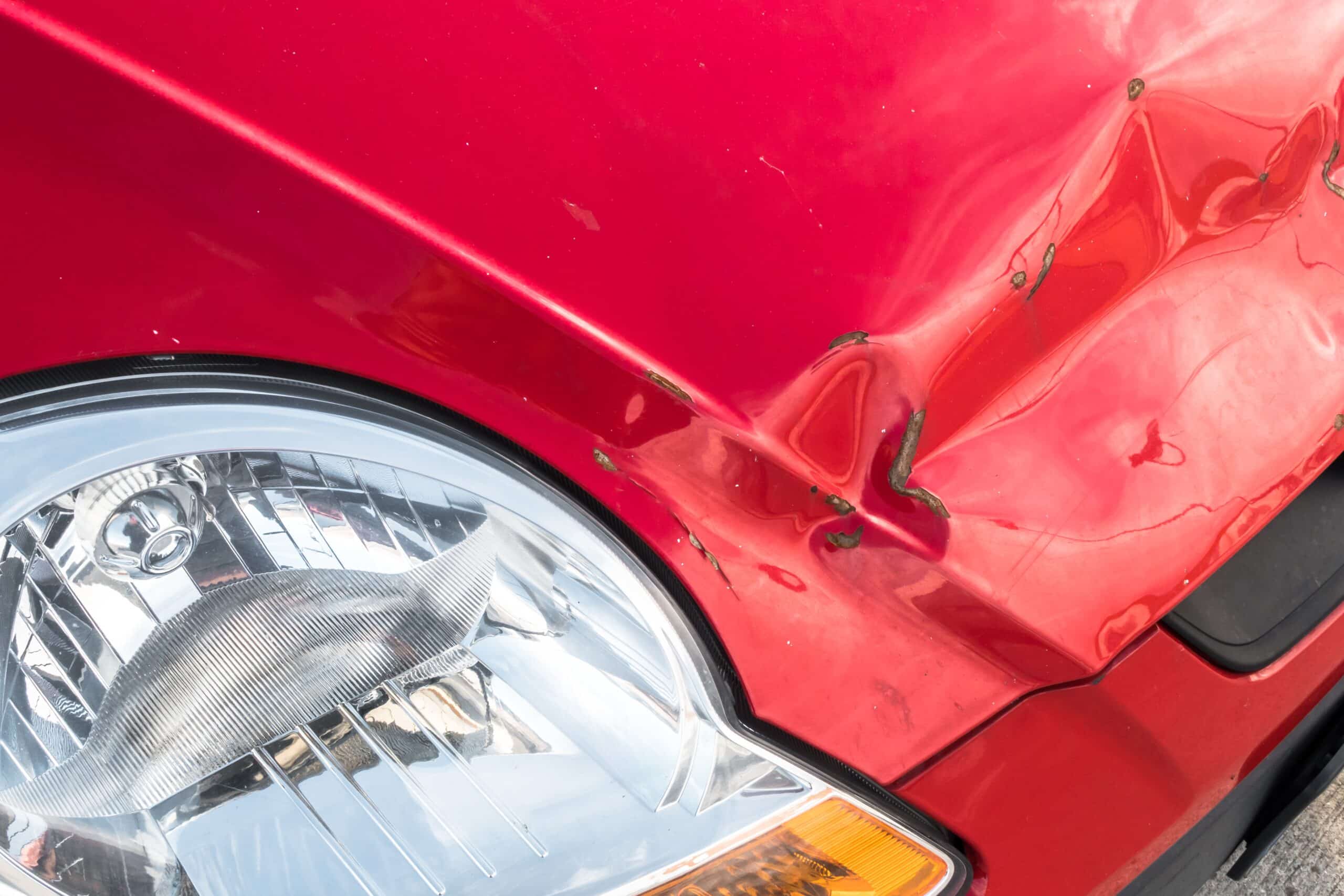 Red car with visible dents and scratches.